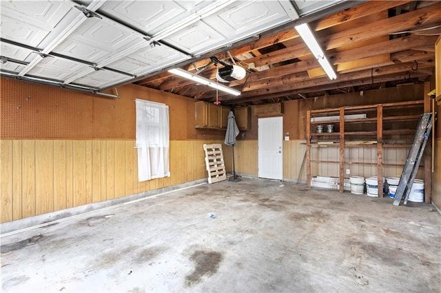 garage with a garage door opener and wood walls