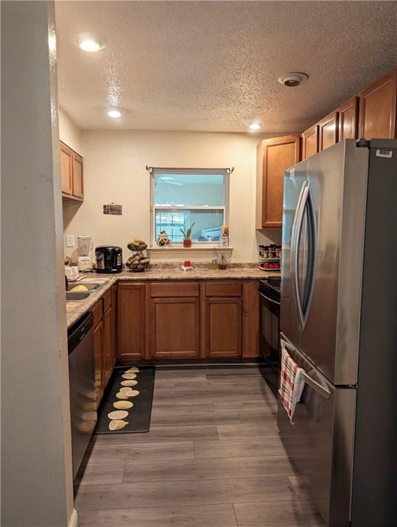 kitchen featuring a textured ceiling, appliances with stainless steel finishes, and light wood-type flooring