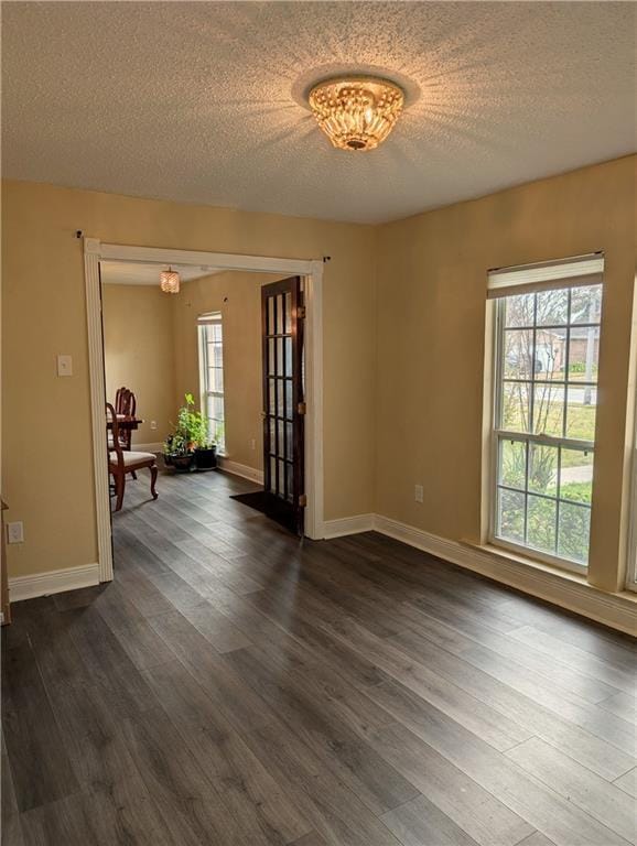 unfurnished room with a notable chandelier, dark hardwood / wood-style flooring, and a textured ceiling