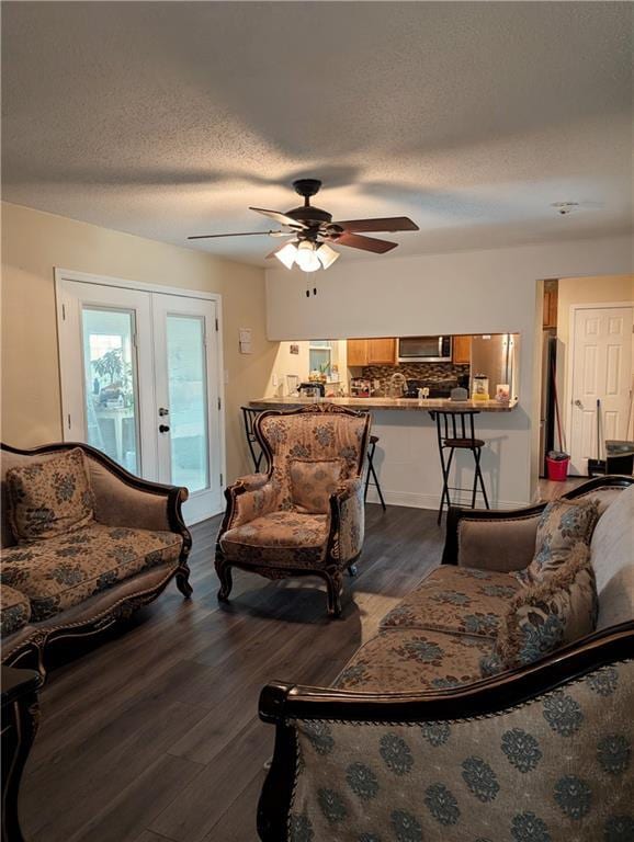 living room with ceiling fan, dark wood-type flooring, a textured ceiling, and french doors