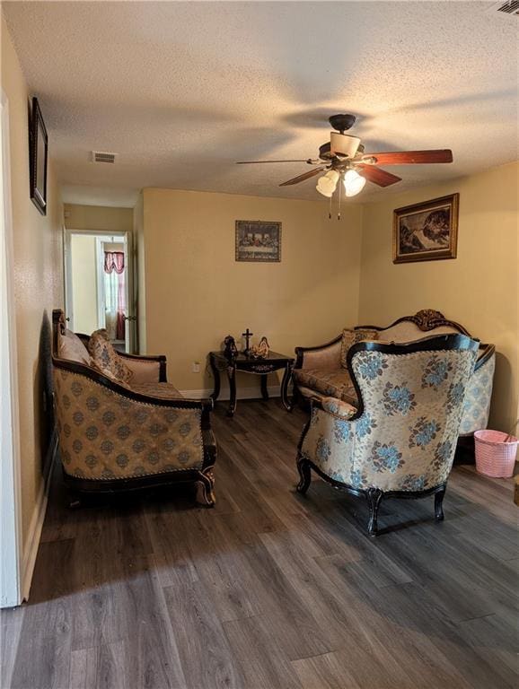 sitting room with ceiling fan, dark wood-type flooring, and a textured ceiling