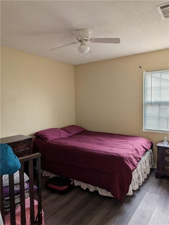 bedroom with ceiling fan, wood-type flooring, and a textured ceiling