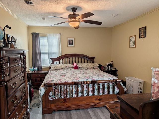 bedroom with a textured ceiling, ceiling fan, ornamental molding, and wood-type flooring