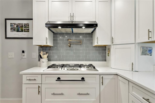 kitchen featuring white cabinets, ventilation hood, stainless steel gas stovetop, and tasteful backsplash