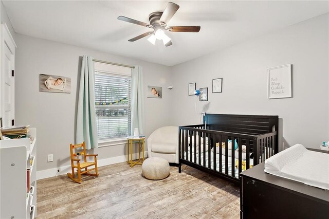 bedroom with ceiling fan, light hardwood / wood-style flooring, and a nursery area