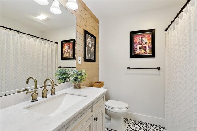 bathroom featuring toilet, vanity, tile patterned floors, and wooden walls