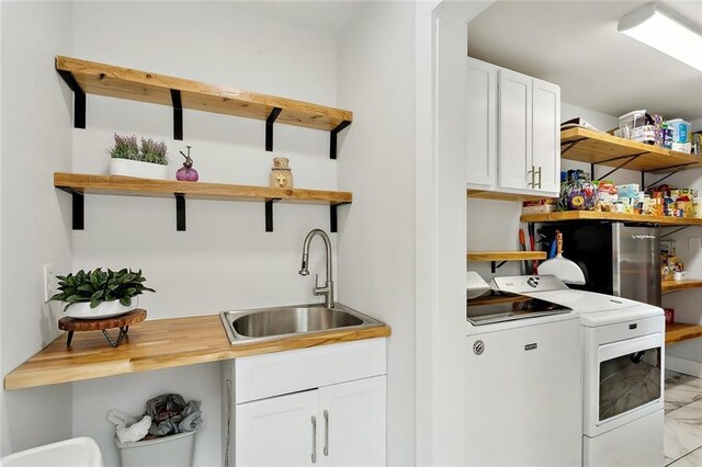 clothes washing area featuring cabinets, washing machine and clothes dryer, and sink