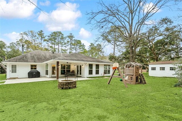 rear view of property featuring a playground, an outdoor structure, a fire pit, and a patio