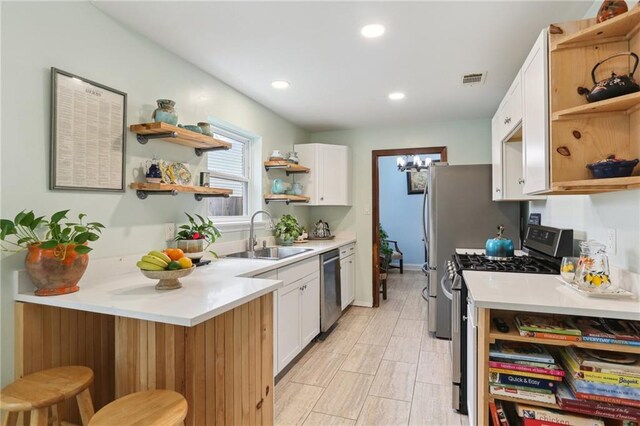 kitchen with sink, a breakfast bar, white cabinets, and stainless steel appliances