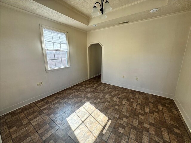 unfurnished room featuring a textured ceiling, ornamental molding, a raised ceiling, and a chandelier