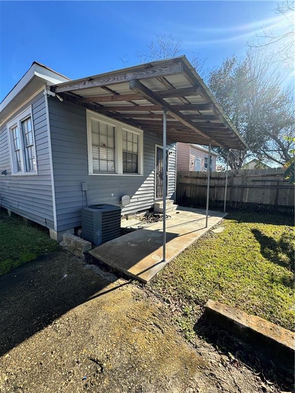 view of front facade with cooling unit and a front lawn