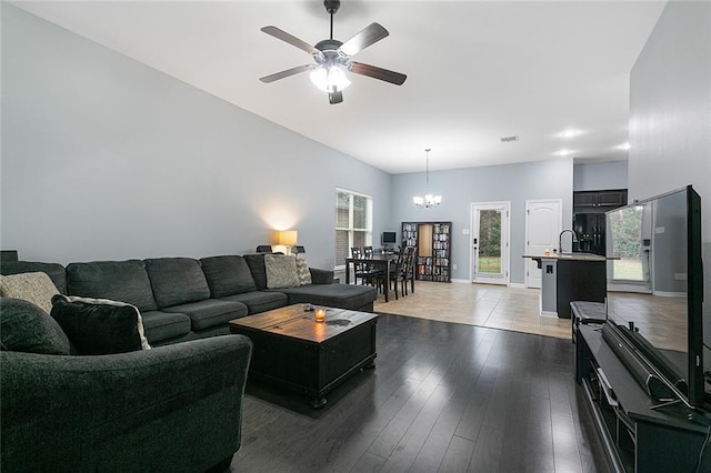 living room with ceiling fan with notable chandelier, sink, and dark wood-type flooring