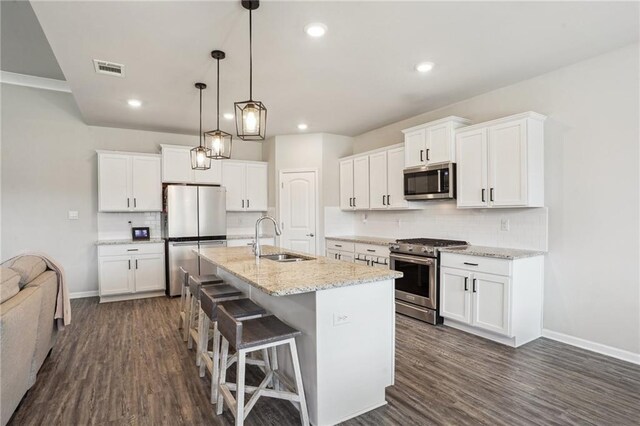 kitchen with sink, hanging light fixtures, a kitchen island with sink, stainless steel appliances, and white cabinets