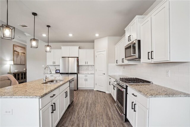 kitchen featuring decorative light fixtures, sink, white cabinets, and appliances with stainless steel finishes