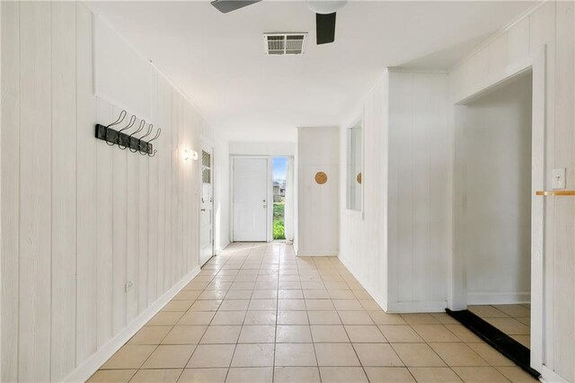 interior space featuring ceiling fan and wooden walls