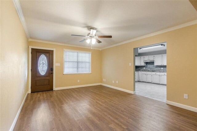 foyer with ceiling fan, wood-type flooring, and crown molding