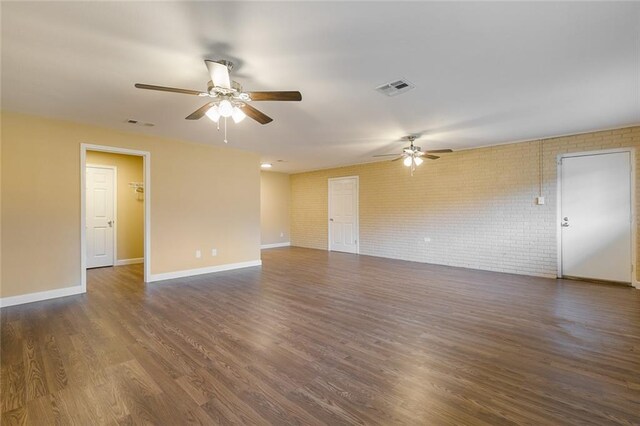 unfurnished room with ceiling fan, brick wall, and dark hardwood / wood-style flooring