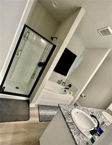 bathroom with independent shower and bath, vanity, and wood-type flooring