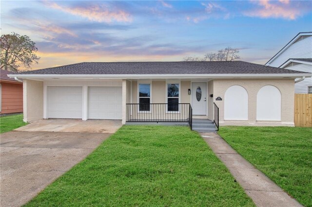 ranch-style home with a garage, a porch, and a lawn