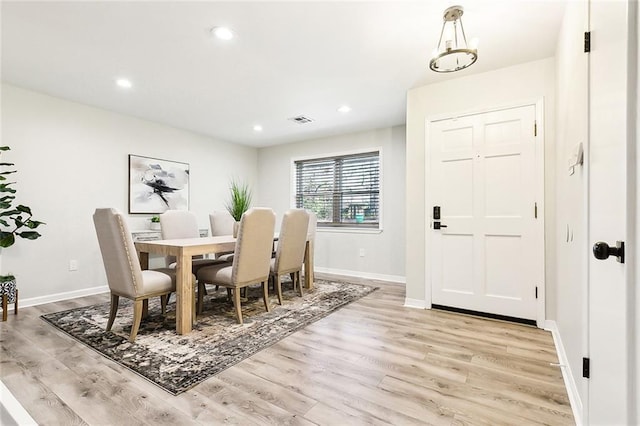 dining area with light hardwood / wood-style flooring and a notable chandelier