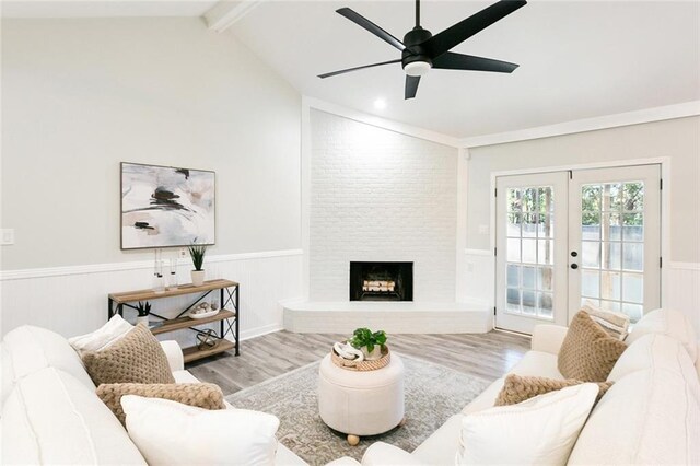 living room with hardwood / wood-style flooring, lofted ceiling, french doors, and a fireplace