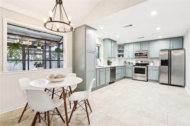 kitchen featuring appliances with stainless steel finishes, lofted ceiling, sink, hanging light fixtures, and a notable chandelier