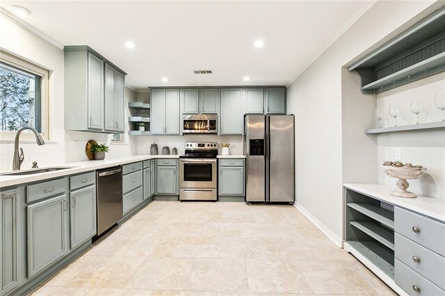 kitchen featuring sink, backsplash, appliances with stainless steel finishes, and gray cabinets