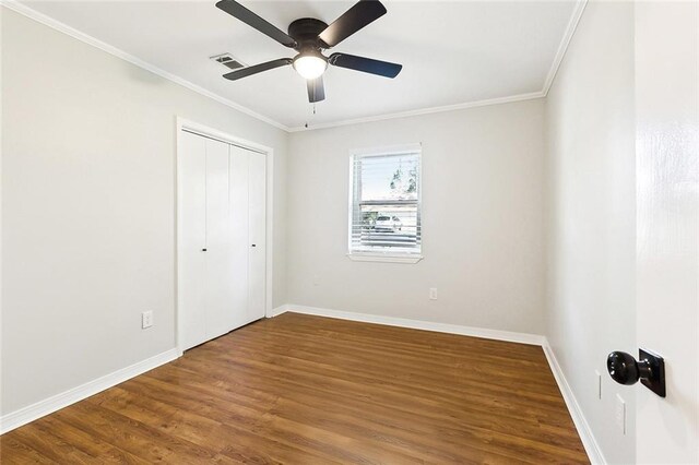 unfurnished bedroom with ceiling fan, wood-type flooring, crown molding, and a closet