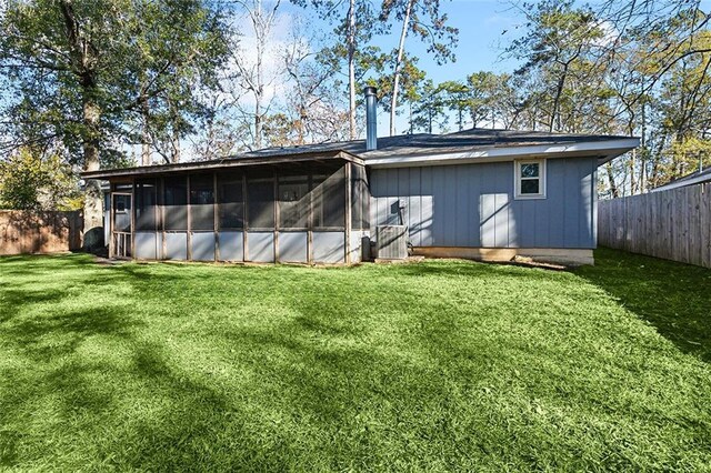 back of house featuring a lawn and a sunroom