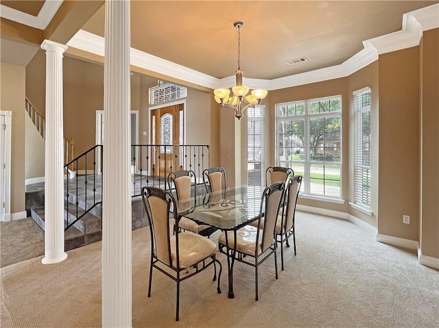 carpeted dining space with ornamental molding, decorative columns, and a chandelier