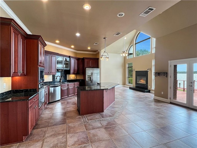 kitchen featuring a kitchen island, pendant lighting, stainless steel appliances, a water view, and french doors