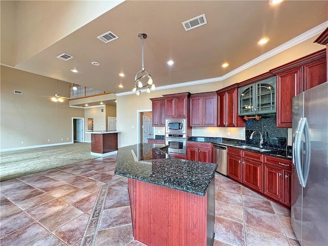 kitchen featuring appliances with stainless steel finishes, sink, decorative backsplash, ornamental molding, and a center island