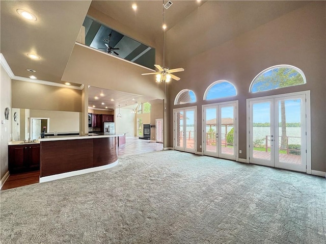 kitchen featuring french doors, stainless steel fridge with ice dispenser, ceiling fan, carpet flooring, and a towering ceiling