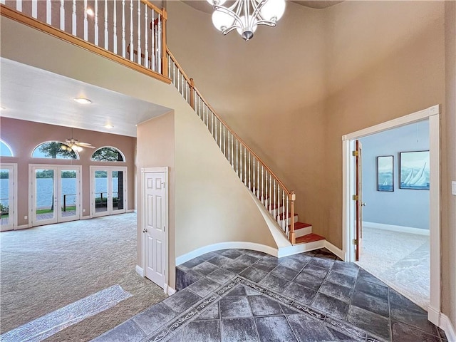 staircase featuring french doors, a water view, carpet flooring, and a high ceiling