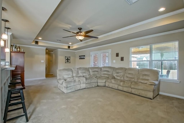 living room with a raised ceiling, ceiling fan, carpet floors, and ornamental molding