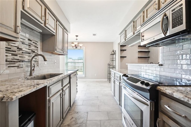 kitchen featuring decorative light fixtures, sink, stainless steel appliances, light stone countertops, and an inviting chandelier