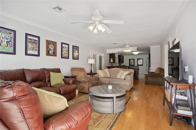 living room with ceiling fan, ornamental molding, and light hardwood / wood-style flooring