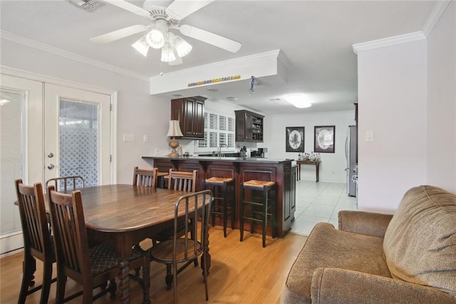 dining area featuring ceiling fan, light wood-type flooring, sink, and ornamental molding