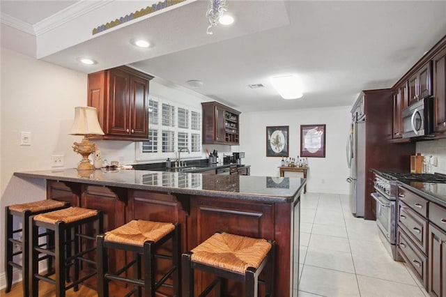 kitchen featuring kitchen peninsula, stainless steel appliances, crown molding, a breakfast bar, and sink