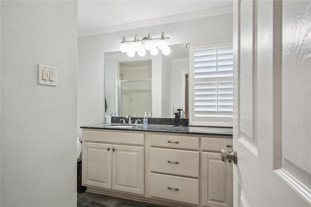 bathroom featuring a shower with door, vanity, and ornamental molding