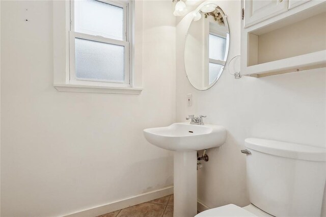 bathroom with a wealth of natural light, toilet, and tile patterned flooring