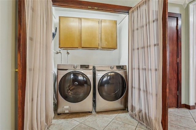 laundry room featuring cabinets, light tile patterned floors, and washer and dryer