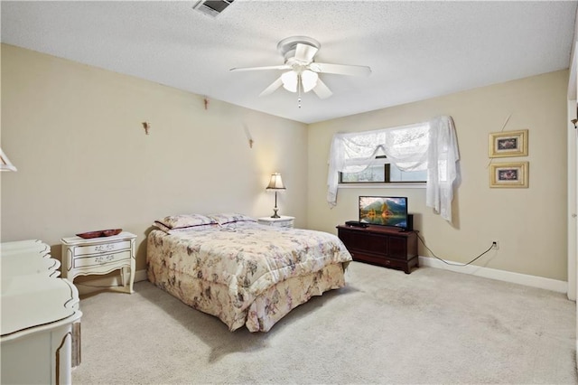 bedroom with ceiling fan, light carpet, and a textured ceiling