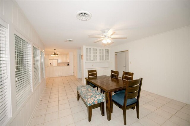 tiled dining space with ceiling fan with notable chandelier