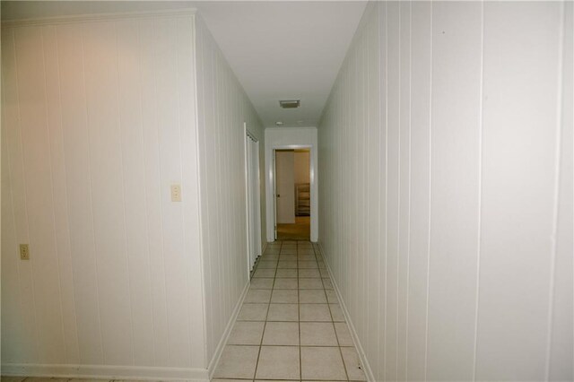 corridor with light tile patterned floors and wood walls