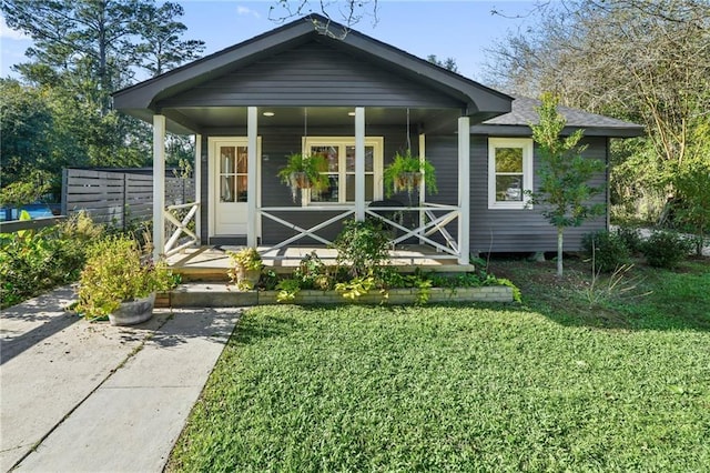 rear view of house featuring a lawn and a porch