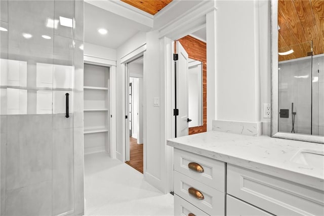 bathroom featuring a shower with shower door and vanity