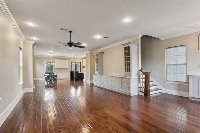 unfurnished living room featuring ceiling fan, crown molding, and a healthy amount of sunlight