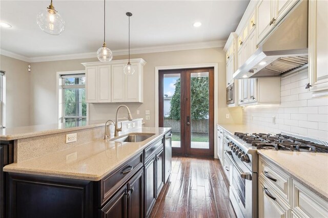 kitchen featuring appliances with stainless steel finishes, french doors, hanging light fixtures, light stone countertops, and sink