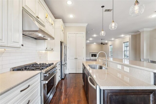 kitchen featuring white cabinetry, appliances with stainless steel finishes, a center island with sink, and decorative light fixtures